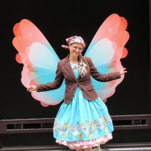 A woman posing wearing a dress and blazer with big fairy wings